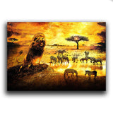 Leinwandbild mit brüllendem Löwen und einer Zebraherde in der Savanne bei einem Sonnenuntergang